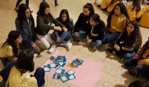 Group of girls sitting on the floor and stickign pictures to a big paper