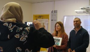 A woman taking a picture of two teachers presenting