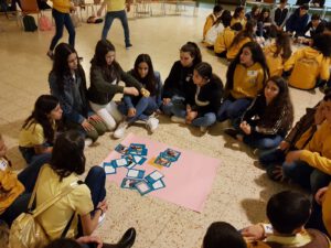 Group of girls sitting on the floor and stickign pictures to a big paper