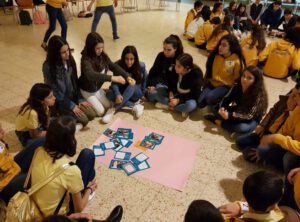 Group of girls sitting on the floor and stickign pictures to a big paper