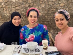 Three women smiling together as they eat together during the month of Ramadan